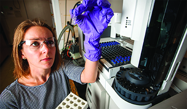 LLNL chemist Sarah Baker holds a gas chromatography vial used to measure the amount of methanol produced by her team’s enzyme-embedded polymer.