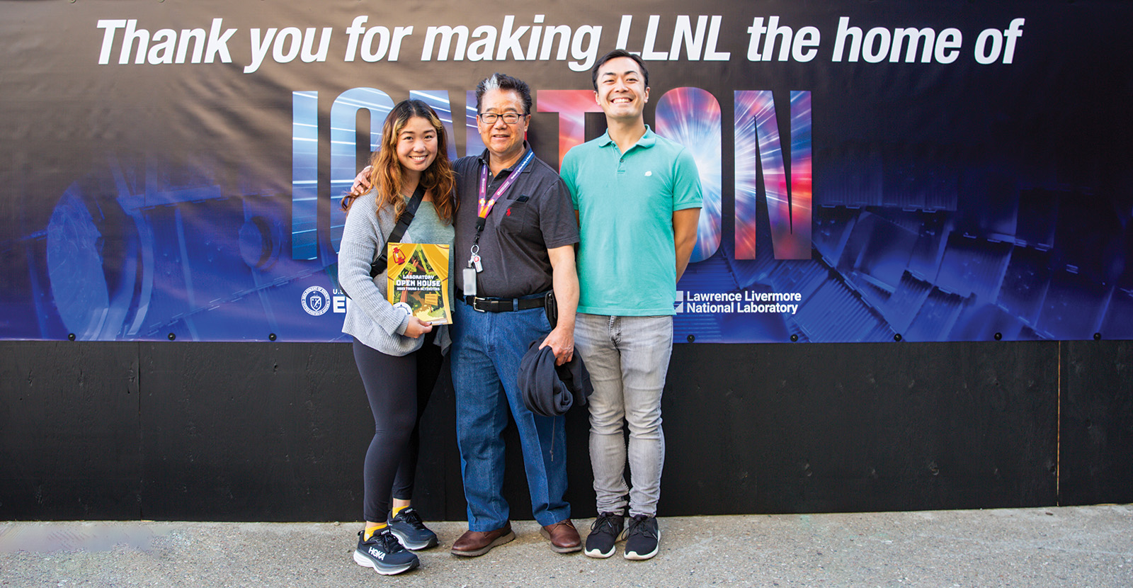 At the Open House, an LLNL employee and guests pose by a poster thanking all employees for their contributions that enabled achievement of ignition.